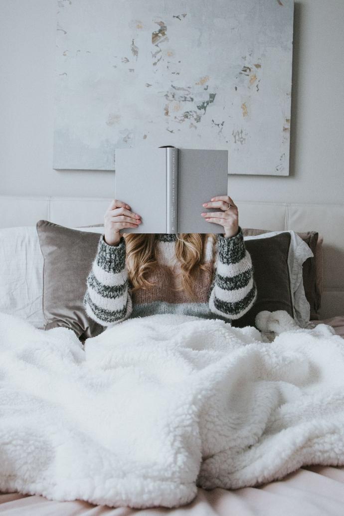 woman sitting on bed while holding book
